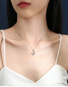 Elegant silver gourd pendant necklace with sparkling stone worn on a female model