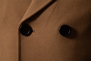 Macro detail of camel wool coat showing double-breasted buttons and twill fabric texture