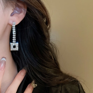 Close-up of elegant silver geometric square drop earrings with shimmering rhinestones
