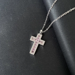 Collana con ciondolo a croce di pietre rosa e catena d'argento su sfondo nero