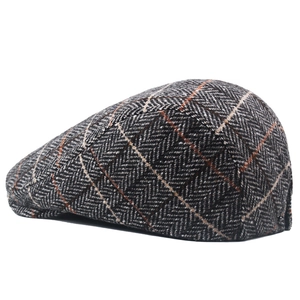 Close-up of gray herringbone wool tweed newsboy cap with orange checked pattern detail
