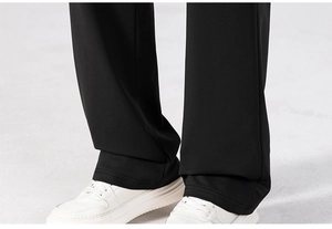 Detail of straight-leg black trousers hem paired with white platform sneakers for casual style