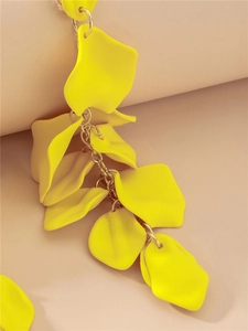 Détail de longues boucles d'oreilles pampilles pétales de rose jaunes mats
