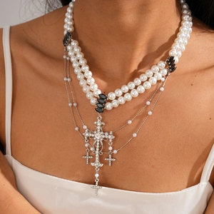 Close-up of double-layer cross necklace with white pearls and sparkling rhinestones