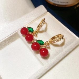 Close-up of red cherry hoop earrings with green leaf gems and white zircon inlay