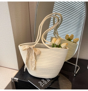 Detail of hand-woven tote bag with lace bow and cream cotton rope texture near mirror