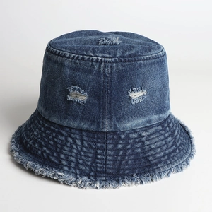 Detail view of frayed edges and distressed denim texture on a blue fisherman bucket hat