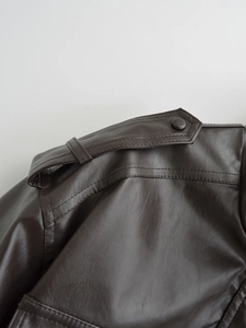 Detail of shoulder epaulets and textured faux leather on dark brown jacket