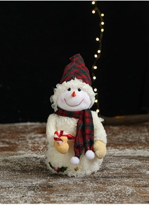 Close-up of Christmas snowman plush with red plaid hat and candy cane on wood