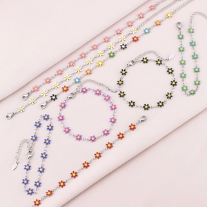 Detailed macro of colorful enamel daisy charms on stainless steel bracelets and anklets