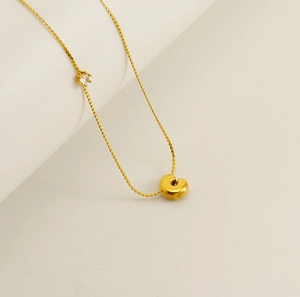 Detail of gold bubble letter necklace with small zircon stone and twisted rope chain