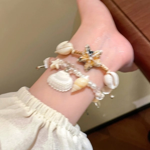 Detail of seashell and starfish charms on a beach style pearl beaded bracelet