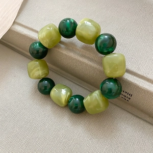 Détail d'un bracelet en perles acryliques vertes avec texture marbrée et style vintage