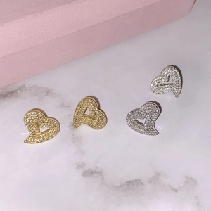 Close-up of heart-shaped stud earrings with pavé zircon in gold and silver plating