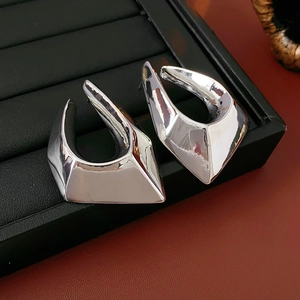 Polished silver geometric earrings with sharp angular facets on black jewelry tray