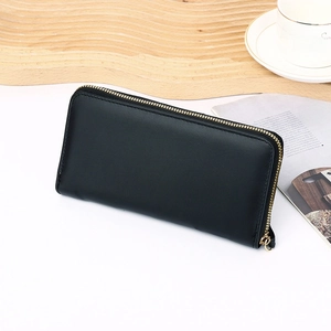 Detail of elegant black leather long wallet with smooth finish and gold zipper closure