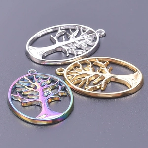 Detailed view of tree of life pendants in silver, gold, and rainbow finishes on dark background