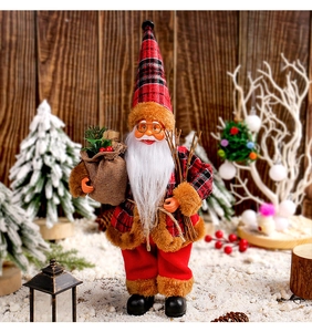 Detail of standing Santa doll with red plaid coat and burlap sack on snowy background