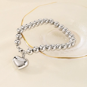 Bracelet à billes argentées avec pendentif cœur poli sur assiette en verre dorée