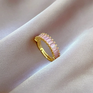 Macro detail of gold-plated geometric ring featuring rectangular pink stones on purple silk