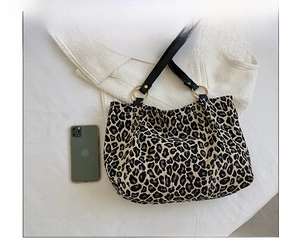Detail view of leopard print tote bag featuring black strap and gold metal ring hardware