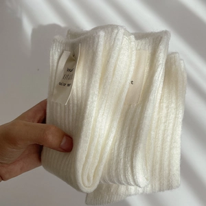 Detailed macro view of white wool-blend socks featuring vertical ribbed knit and fabric label