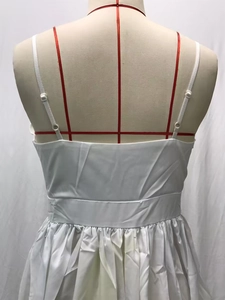 Detailed view of the pleated high-waisted band and gathered hem on a white camisole dress