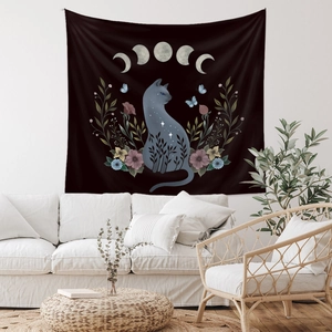 Detail of bohemian black tapestry with cat and moon phases against a white wall