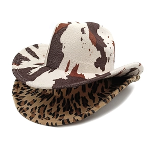 Detail view of two plush western cowboy hats featuring cow print and leopard print patterns
