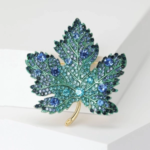Detailed view of maple leaf brooch with green enamel and sparkling rhinestones