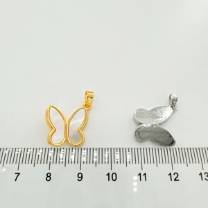 Macro detail of butterfly charms with white shell inlay next to a measuring ruler