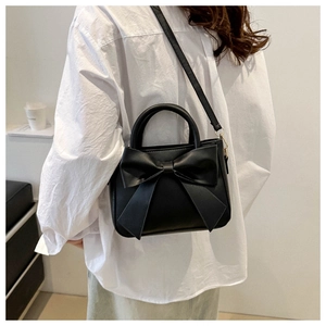Elegant black leather bucket bag with oversized bow, handheld and crossbody style