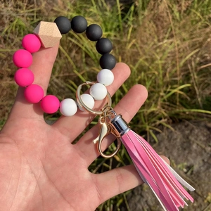 Silicone bead bracelet keychain with pink tassels and wood bead on outdoor grass