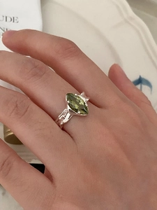 Detail of 925 silver ring featuring olive green zircon and irregular textured finish