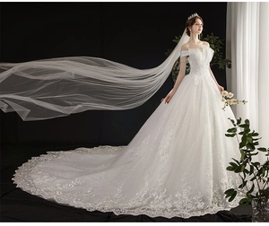 Detail of white off-shoulder wedding dress featuring sequins and long lace embroidered train