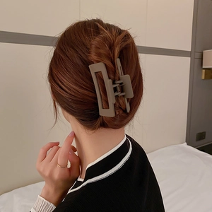 Gros plan d'une grande pince à cheveux carrée gris-brun fixant un chignon pour femme