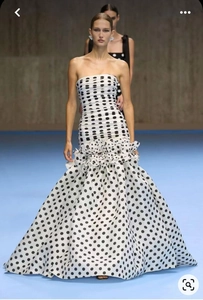 Makro-Detail des eleganten schwarzen Polka-Dot-Musters am weißen Trägerlosen Maxikleid