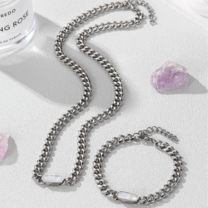 Silver cuban chain necklace and bracelet set with white rectangular shell inlay on white surface