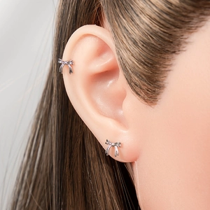Elegant silver bow cartilage stud earrings on model for a minimalist piercing look
