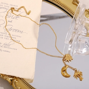 Dettaglio della collana placcata oro 18K con ciondoli a palma, cuore e luna