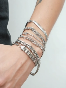 Close-up of stacked 18K silver stainless steel Cuban and snake chain bracelets