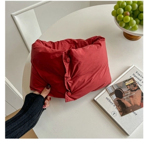 Dettaglio della sciarpa di piumino rosso con tre bottoni su un tavolo bianco con libri