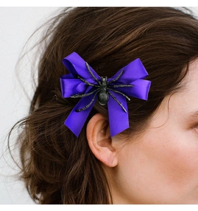 Détail d'une barrette nœud papillon violet avec araignée sur les cheveux d'un modèle