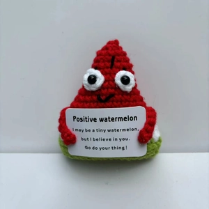 Close-up of handmade crochet positive watermelon doll holding an encouraging message card