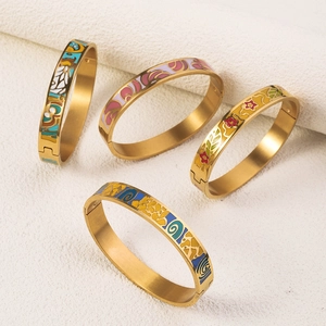 Detailed macro of 18K gold plated bangles with colorful enamel floral and geometric patterns