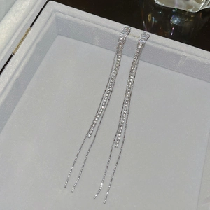 Elegant long silver tassel drop earrings with sparkling cubic zirconia on a gray tray
