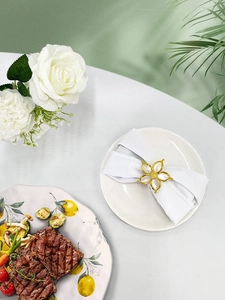 Detailed close-up of golden floral napkin ring with white petals on elegant dining table