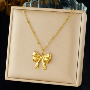 Detalle de un collar chapado en oro con colgante de lazo sobre un estuche de joyería