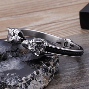 Macro detail of vintage wolf head steel bracelet with black braided leather inlay and spring hinge