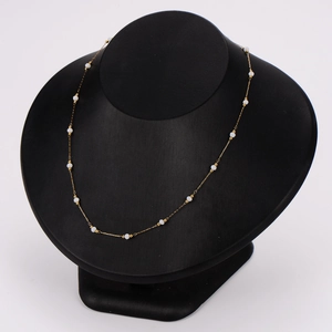 Elegant gold beaded necklace with white pearls displayed on a black jewelry bust stand